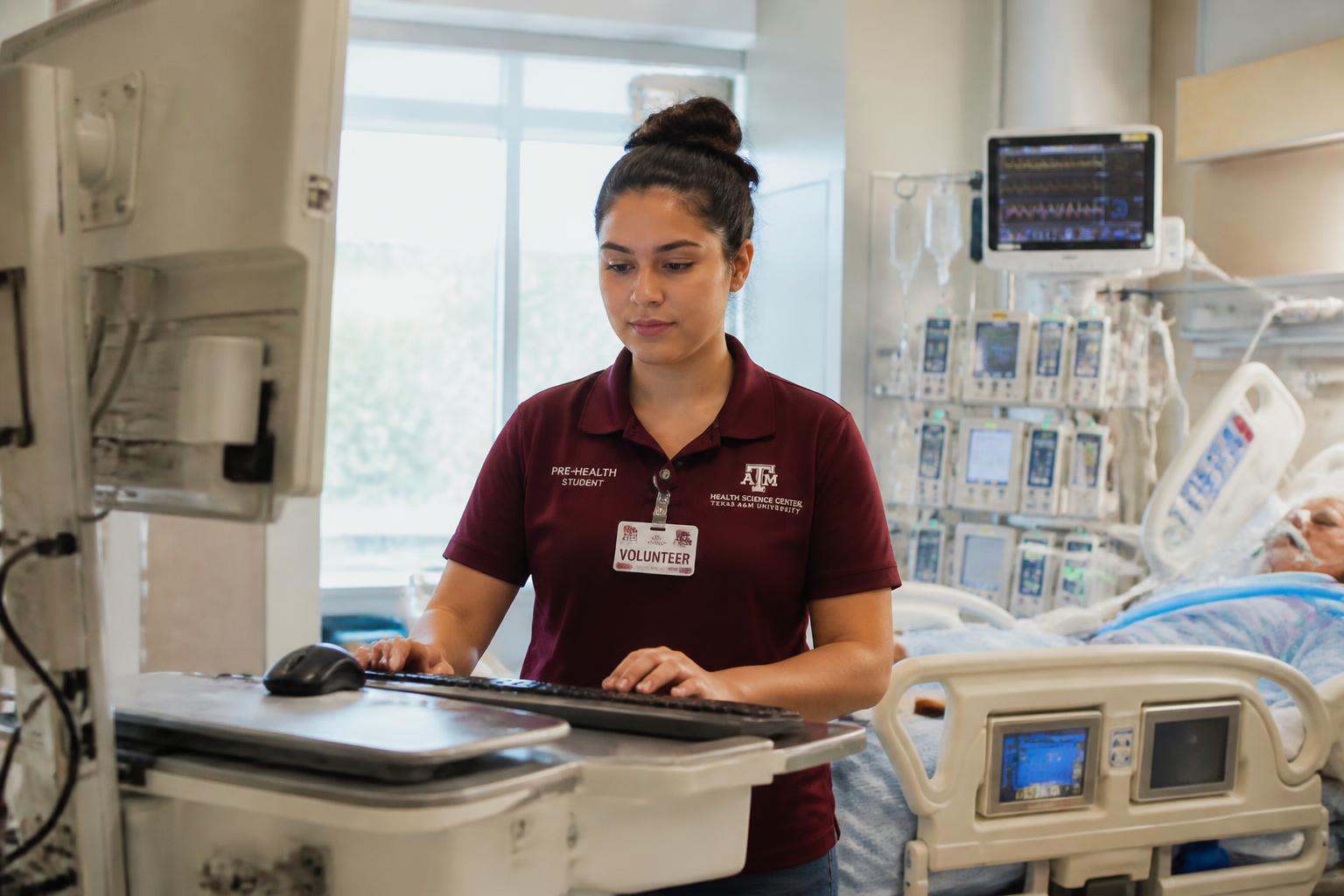A scholar pushing a supply cart down a hospital corridor, badged and on shift.